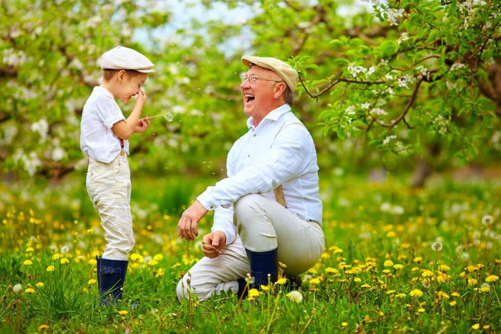 Man and Kid Playing Dandelions in Spring Garden 